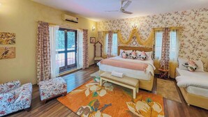 A bedroom with a bed, a bench, a chair, a bedside table, a lamp, and a window. - Casa blu 4BHK Spacez Pool & Garden Villa (Bengaluru)