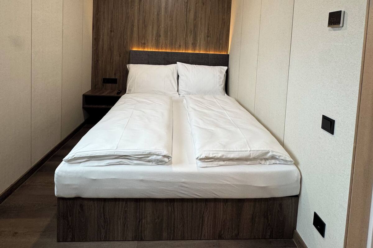 Un dormitorio moderno con una cama grande, cabecera de madera e iluminación empotrada.