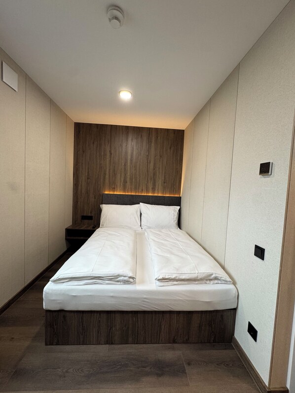 Un dormitorio moderno con una cama grande, cabecera de madera e iluminación empotrada.