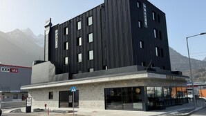 A modern building with a black facade, a ground-level entrance, and a visible restaurant sign. - Cube Alpine Stay (Buers)