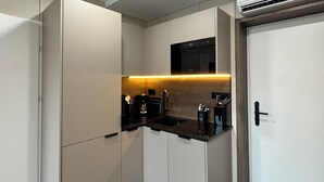 A compact kitchen with a built-in oven, a microwave, and a sink. - Cube Alpine Stay (Buers)