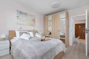 Ein Schlafzimmer mit einem Bett, Nachttischen, einem Kleiderschrank und einer Tür zu einem anderen Raum.