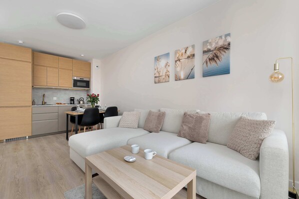 A modern living space with a kitchen, a sofa, a coffee table, and wall art.