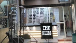 Entrada de un hotel con un cartel que dice 'THE BLISS', un mostrador de recepción y una escalera que conduce a los pisos superiores.