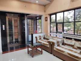 A hotel lobby with a reception desk, sofas, and large windows offering a view of the outdoors.