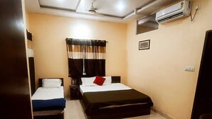 Habitación de hotel con una cama, una cama individual, una mesita de noche, un equipo de aire acondicionado y un ventilador de techo.