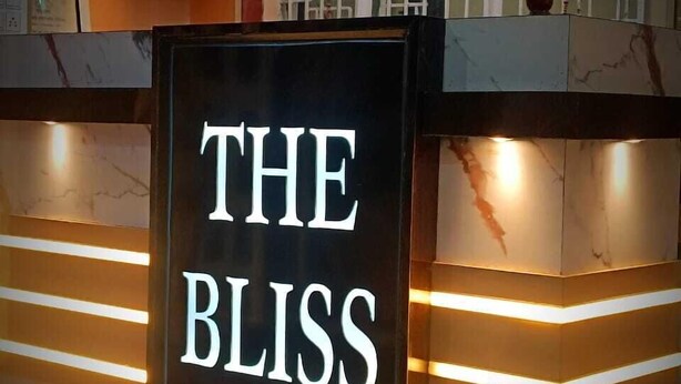 Un mostrador de recepción con un cartel que dice 'THE BLISS' y un florero con flores encima.