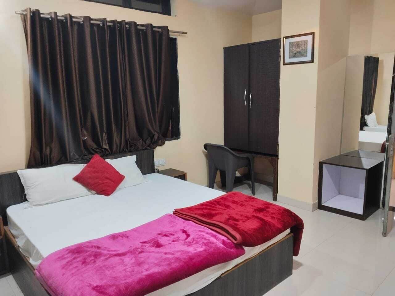 A bedroom with a bed, a desk, a wardrobe, and a mirror.