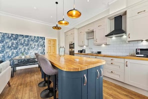 Una cocina moderna con una isla de madera, luces colgantes y armarios blancos.
