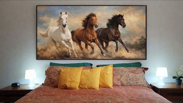 Un lit recouvert d’une couvre-lit à motifs, deux lampes de chevet et un tableau représentant des chevaux accroché au mur.