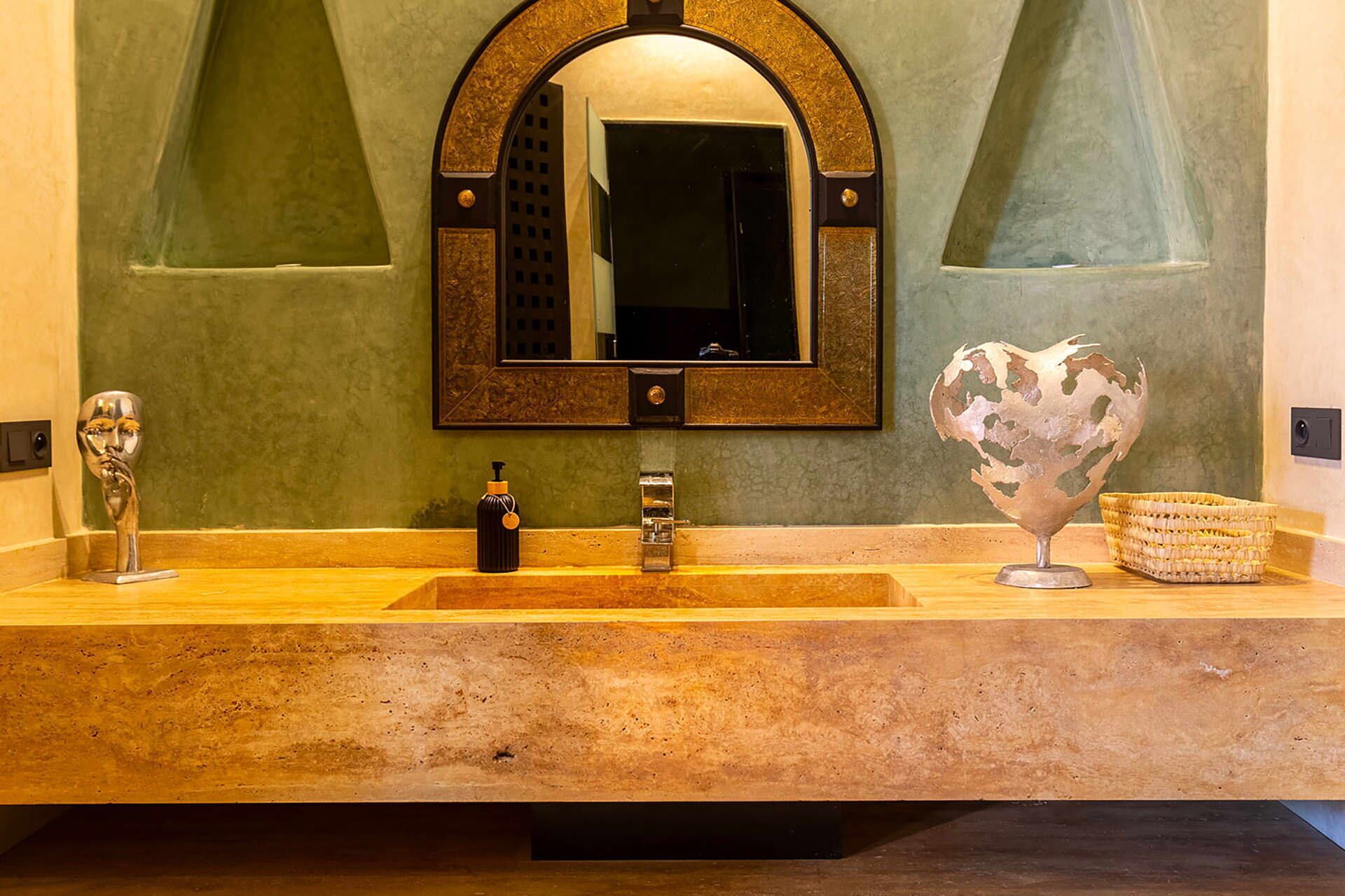 A bathroom with a large mirror, two sinks, a soap dispenser, and a decorative globe.