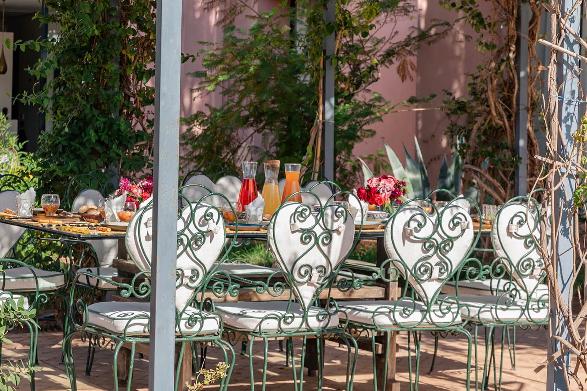 An outdoor dining area with heart-shaped chairs and a table set for breakfast.