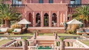 A pool area with lounge chairs, a covered seating area, and a staircase leading to a building entrance. - Villa Dihya pool and jacuzzi - My Rental Homes (Marrakesh)