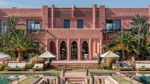 A hotel with a pool, outdoor seating, and palm trees. - Villa Dihya pool and jacuzzi - My Rental Homes (Marrakesh)