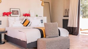 A bedroom with a bed, bedside tables, a nightstand, a chair, and a window with curtains. - Villa Dihya pool and jacuzzi - My Rental Homes (Marrakesh)
