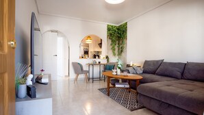 Ett modernt vardagsrum med en soffa, ett soffbord och en matplats med en stol och ett bord.
