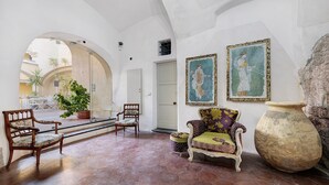 An interior with arched ceilings, a seating area with chairs, a large vase, and framed artwork on the walls. - Duke Room in Pietra Ligure Castle (Pietra Ligure)