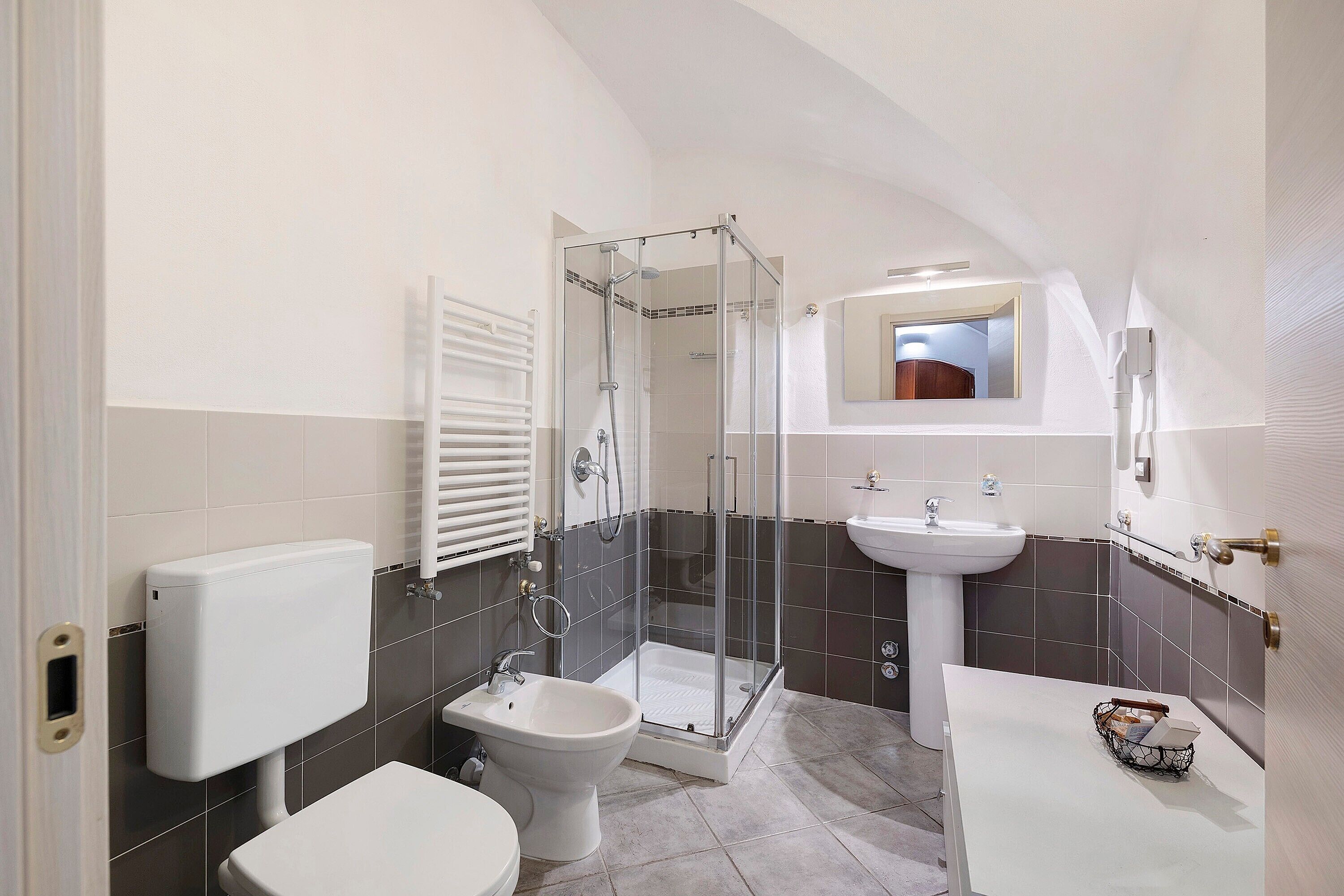 Un bagno con WC, bidet, doccia e lavandino.