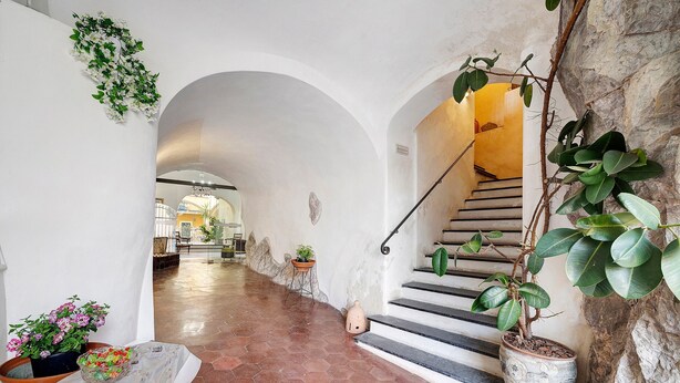 A hallway with a tiled floor, a staircase, and potted plants. - Marchese Room with Shared Terrace (Pietra Ligure)