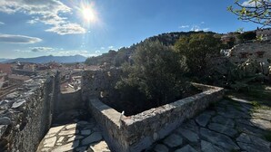 An ancient stone structure with a stone-paved pathway, surrounded by greenery and overlooking a town. - Marchese Room with Shared Terrace (Pietra Ligure)