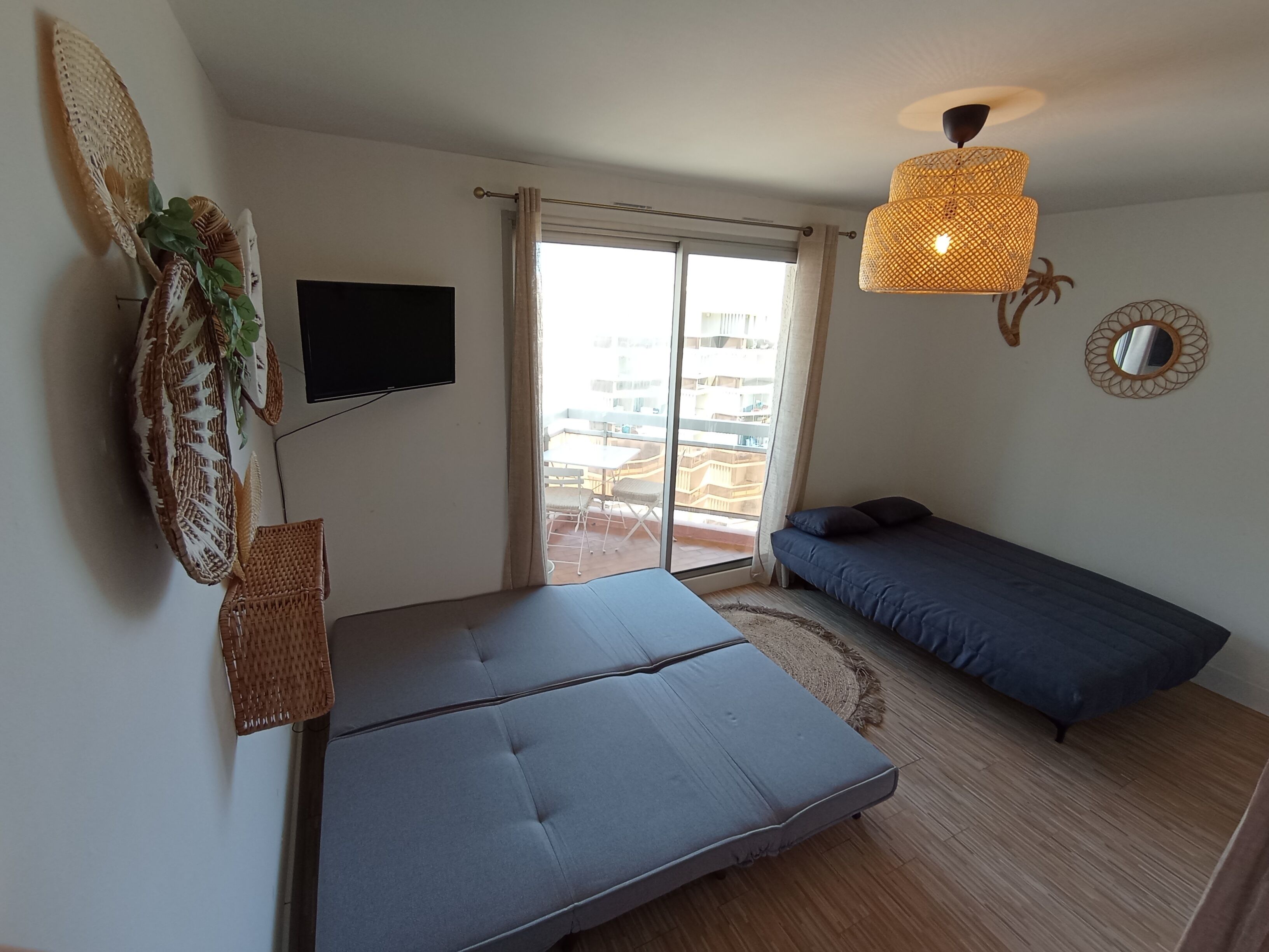 A room with a bed, a TV, a window with curtains, a ceiling light, and a wall decoration.