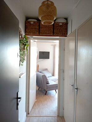 A hallway leading to a bedroom with a bed, a television, and a wicker basket on the ceiling. - Mar Playa y Sol (Canet-en-Roussillon)