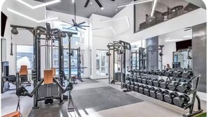 Ein modernes Fitnessstudio mit unterschiedlichen Trainingsgeräten, einem Spiegel und einer Hantelbank.