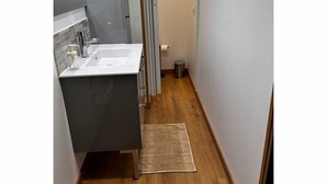 Une petite salle de bain avec un lavabo blanc, un miroir et un plancher en bois.