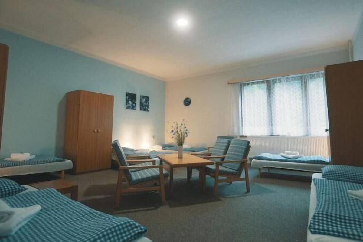 Une pièce comprenant un lit, une armoire en bois, une table avec des chaises et une fenêtre avec des rideaux.