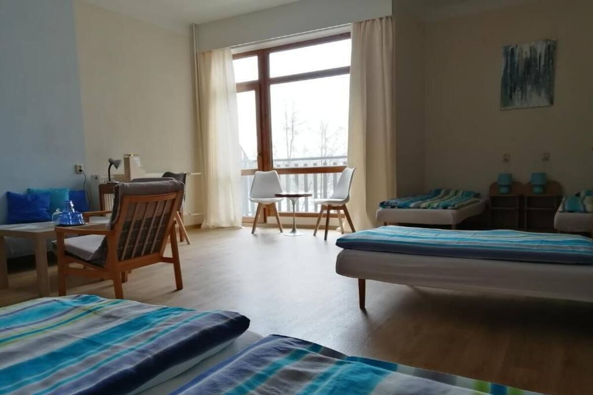 Une chambre d’hôtel avec une grande fenêtre, un lit, un bureau avec une chaise et une petite table.