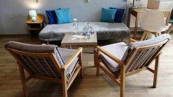 A room with a sofa, two armchairs, a small table, and a lamp.