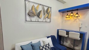 Ein modernes Wohnzimmer mit einer Couch, einem Couchtisch, einem gemusterten Teppich und einem an der Wand hängenden Kunstwerk.