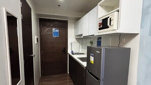 Eine kleine Küche mit Mikrowelle, Kühlschrank und Spüle.