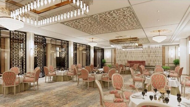 A spacious banquet hall with round tables, chairs, and chandeliers.