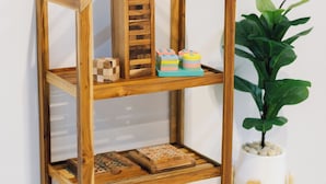 A wooden bookshelf with multiple shelves, a potted plant, and a small stool.