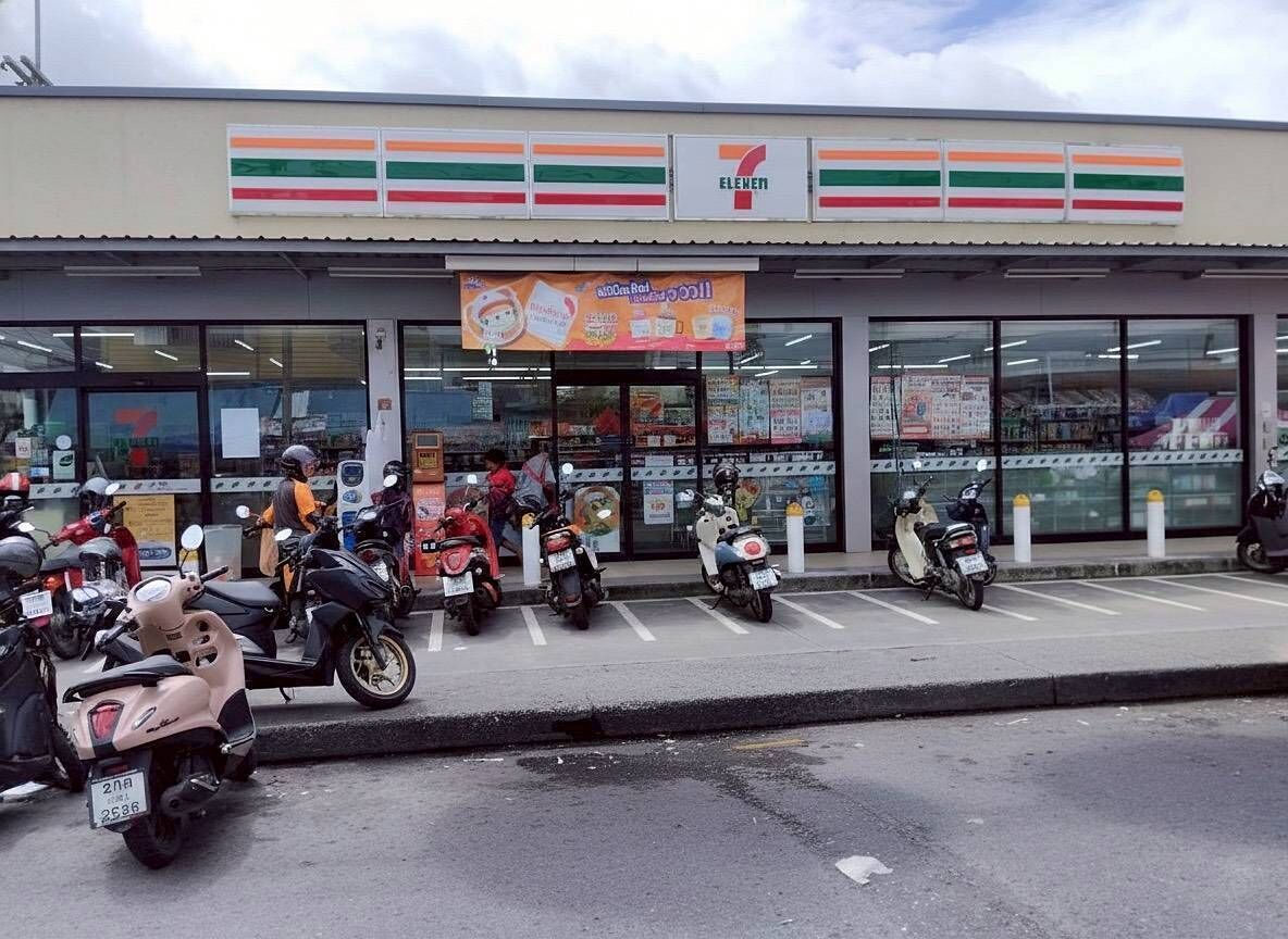 Un negozio di alimentari 7-Eleven con un parcheggio pieno di scooter.