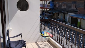 A balcony with a chair, a small table, and a view of the street below.