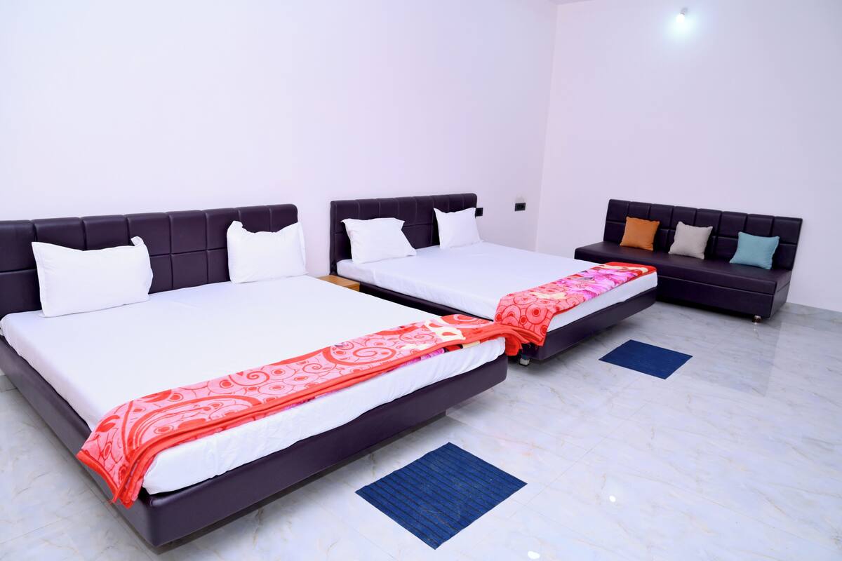 A hotel room with two beds, each with a headboard, white bedding, and a red patterned throw.