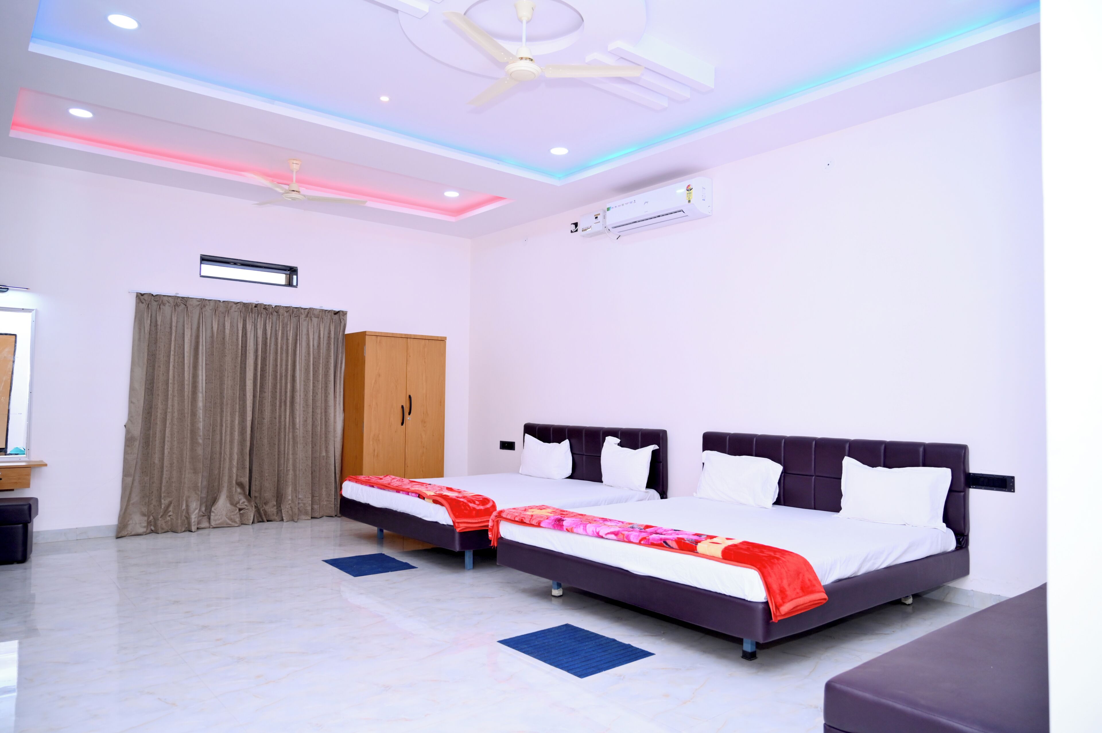 Een hotelkamer met twee bedden, een plafondventilator, een airconditioning en een kledingkast.
