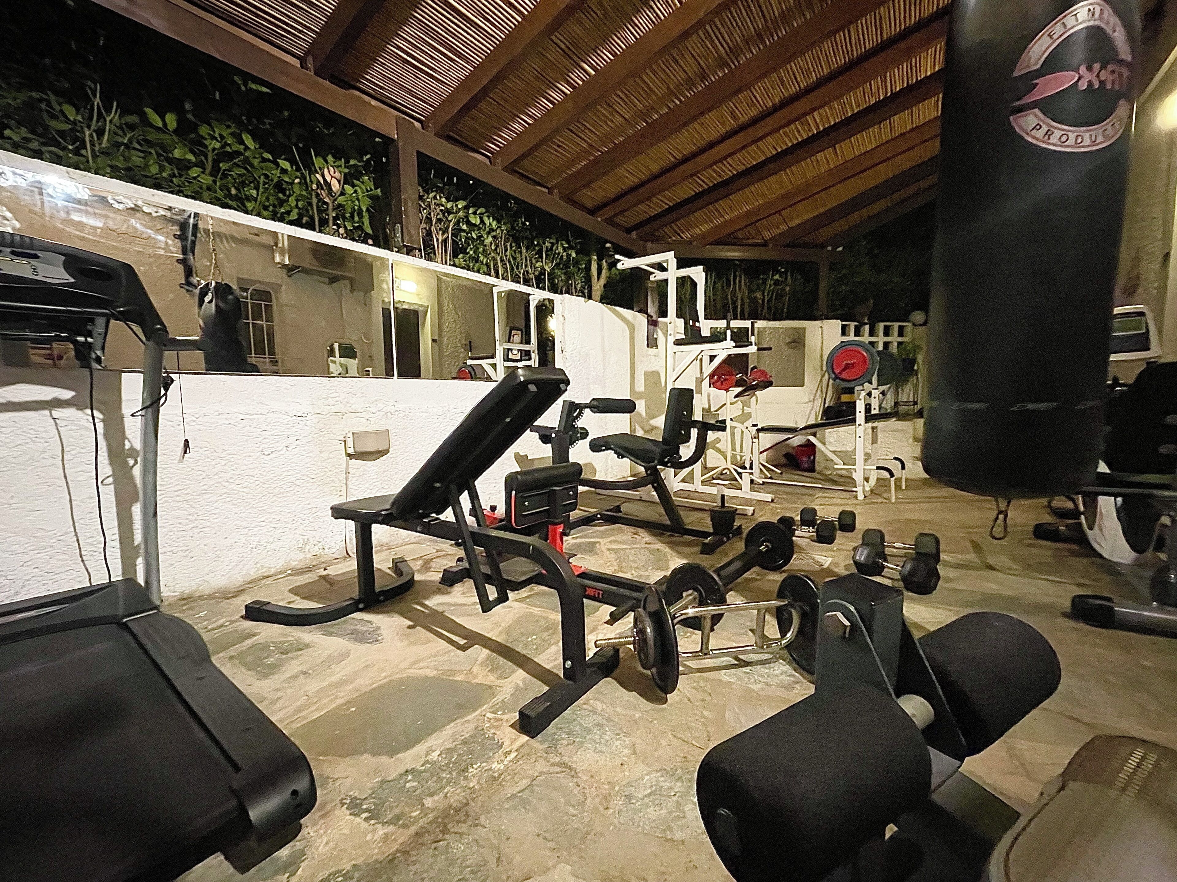 A gym with various exercise equipment, including benches, dumbbells, and weight machines.
