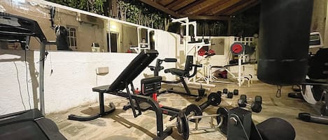 A gym with various exercise equipment, including benches, dumbbells, and weight machines.