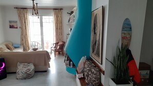 A room with a bed, a sofa, a chair, a table, and a surfboard. - Captain Jack’s Seaside Villa (Nea Makri)