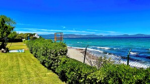 A coastal landscape with a chair, grass, and a fence. - Captain Jack’s Seaside Villa (Nea Makri)