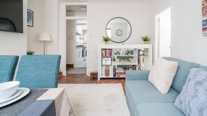 Un salon comprenant un canapé, des fauteuils, une table basse, une bibliothèque et un miroir.