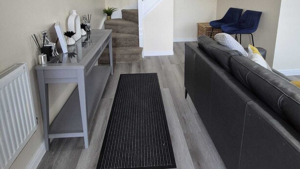 Ett modernt vardagsrum med en trappa, en soffa, ett soffbord och en matplats.