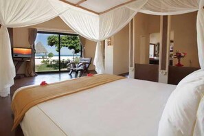 A room with a bed, a TV, a desk, and a view of the beach. - Gold Zanzibar Beach House and Spa (Kendwa)