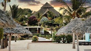 Un resort con un edificio en forma de pirámide, palmeras y sombrillas de paja.
