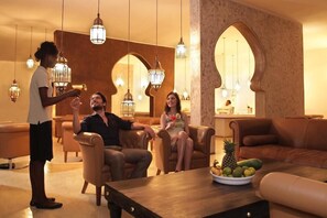 A modern lounge with leather sofas, a wooden coffee table with fruit, and decorative lighting. - Gold Zanzibar Beach House and Spa (Kendwa)