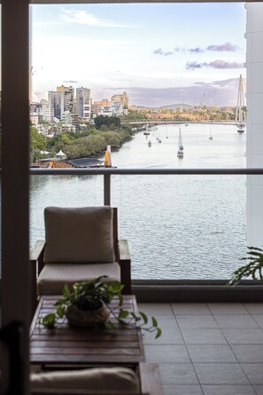 A balcony with a view of a river, boats, and a bridge. - Tropical City Escape (Brisbane)