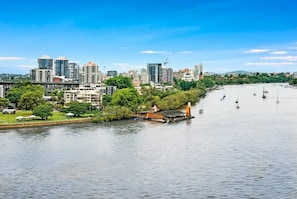 Un río con barcos, el horizonte de una ciudad y un parque con árboles.